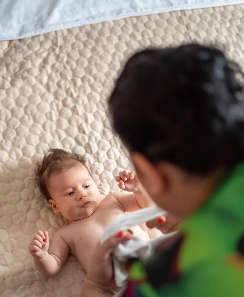Bebelușul este pregătit pentru botez, pe o pătură matlasată