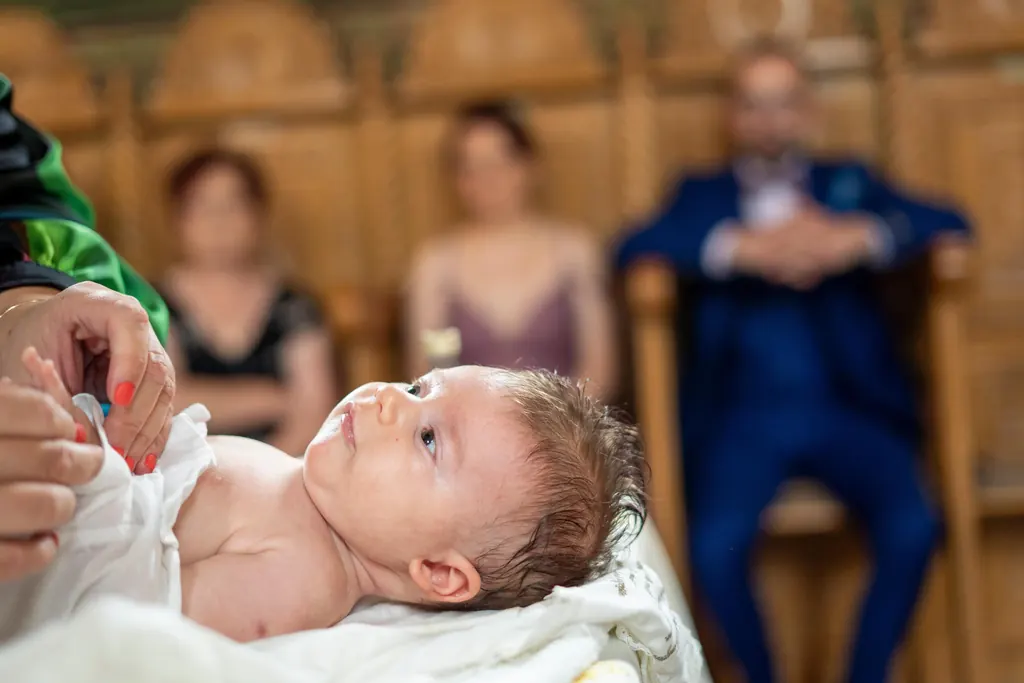 Bebelușul în biserică, cu invitații în fundal