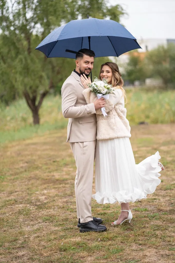 Mirii sub o umbrelă, pe o pajiște, în ziua cununiei civile