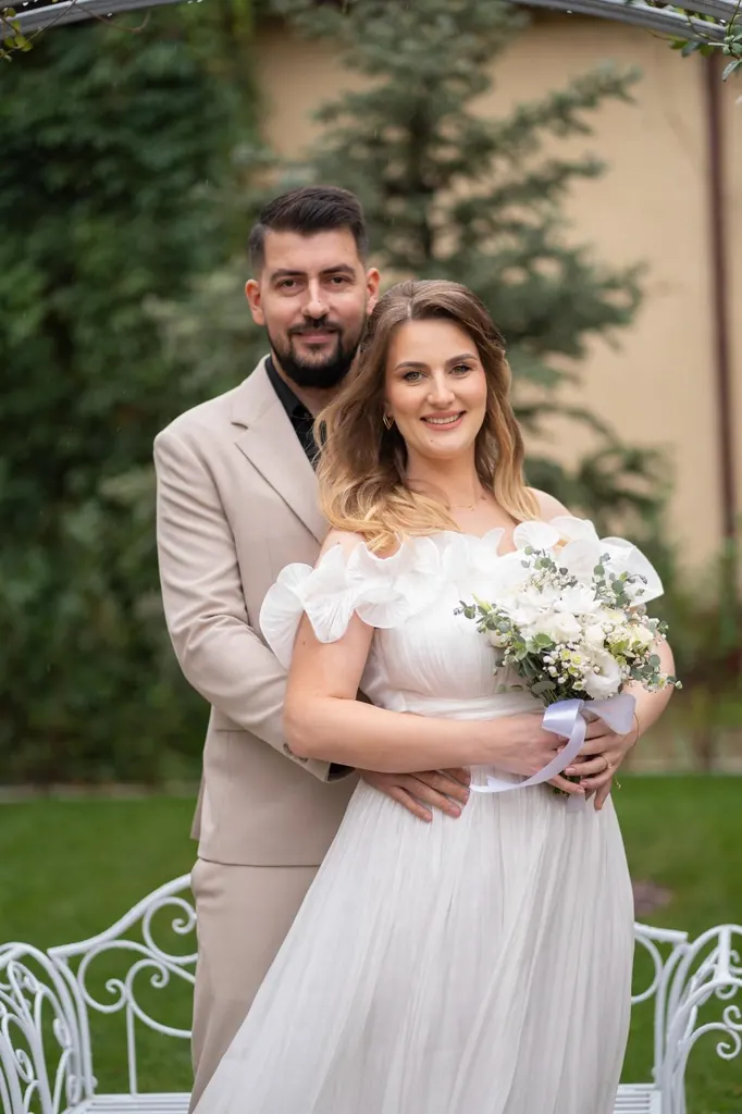 Mirii îmbrățișați în grădină, mireasa cu buchet de flori albe