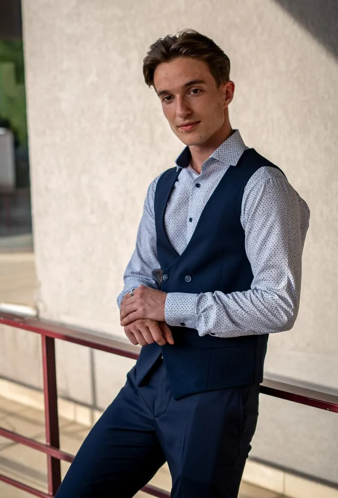 Tânăr în vestă bleumarin, sprijinit de o balustradă