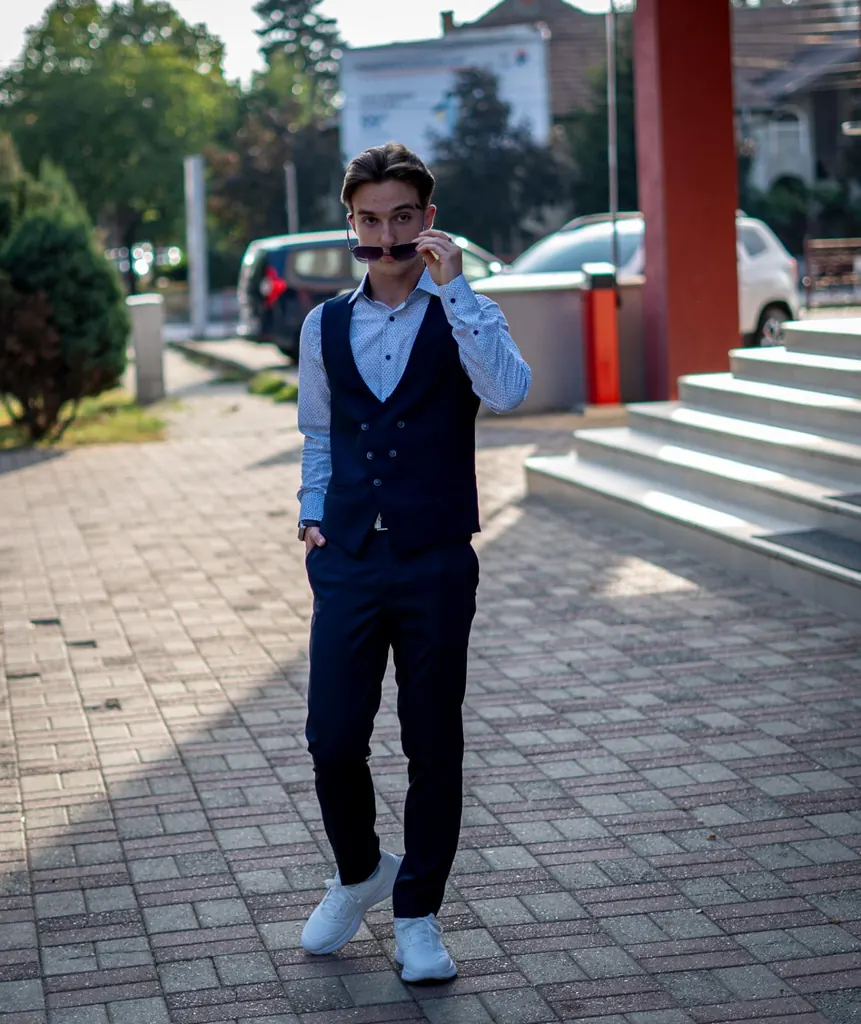 Tânăr care își potrivește ochelarii de soare, cu un zâmbet jucăuș