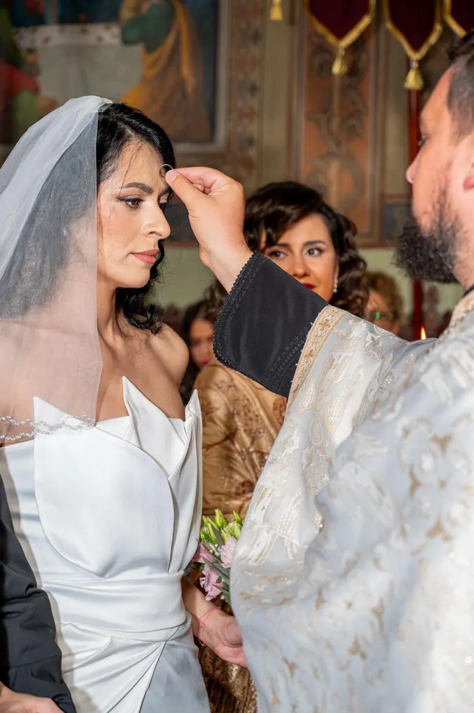 Preotul o miruiește pe mireasă în timpul slujbei