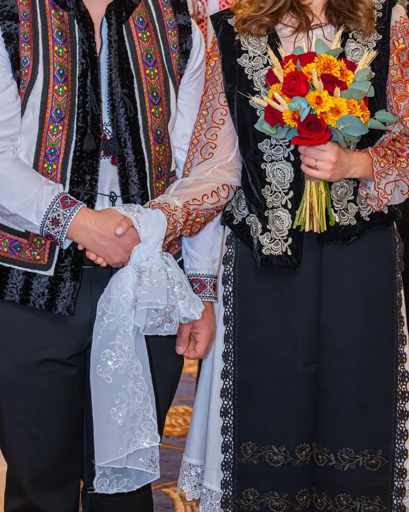 Mâinile mirilor în costume populare, unite cu ștergarul brodat